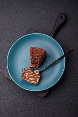 Lezzetli taze cheesecake keki ya da koyu beton arka planda seramik tabakta kremalı ve fındıklı snickers.