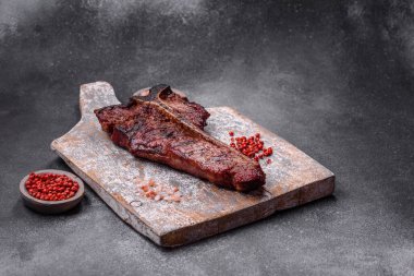 Lezzetli biftek, tuz, baharat ve otlarla birlikte koyu beton bir arka planda.