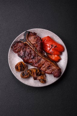 Lezzetli biftek, tuz, baharat ve otlarla birlikte koyu beton bir arka planda.