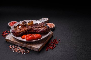 Lezzetli biftek, tuz, baharat ve otlarla birlikte koyu beton bir arka planda.