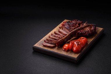 Lezzetli biftek, tuz, baharat ve otlarla birlikte koyu beton bir arka planda.