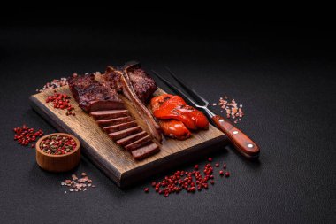 Lezzetli biftek, tuz, baharat ve otlarla birlikte koyu beton bir arka planda.