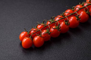 Siyah beton bir arka planda evde yemek pişirmek için kullanılan olgun kırmızı kiraz domatesleri.