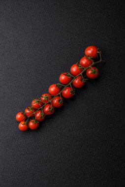 Siyah beton bir arka planda evde yemek pişirmek için kullanılan olgun kırmızı kiraz domatesleri.