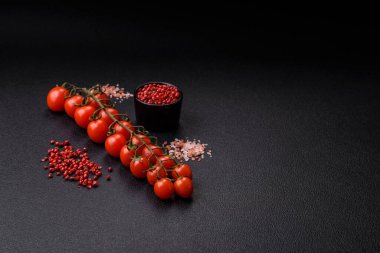 Siyah beton bir arka planda evde yemek pişirmek için kullanılan olgun kırmızı kiraz domatesleri.