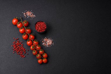 Siyah beton bir arka planda evde yemek pişirmek için kullanılan olgun kırmızı kiraz domatesleri.