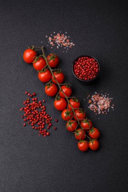 Siyah beton bir arka planda evde yemek pişirmek için kullanılan olgun kırmızı kiraz domatesleri.