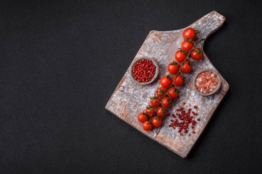 Siyah beton bir arka planda evde yemek pişirmek için kullanılan olgun kırmızı kiraz domatesleri.