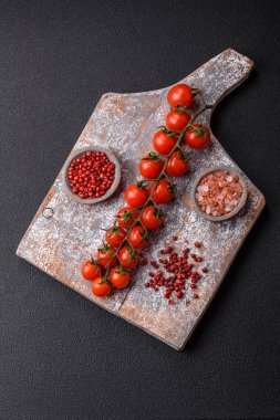 Siyah beton bir arka planda evde yemek pişirmek için kullanılan olgun kırmızı kiraz domatesleri.