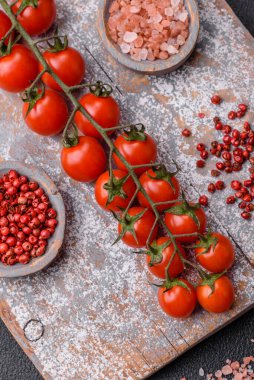 Siyah beton bir arka planda evde yemek pişirmek için kullanılan olgun kırmızı kiraz domatesleri.