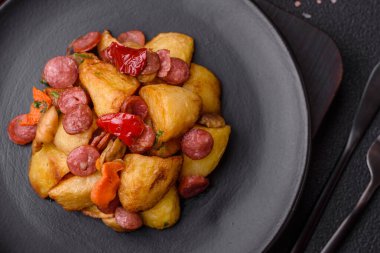 Izgara patates dilimlenmiş, sarımsak, soğan, tuz, baharat ve çimento kaplı sosislerle birlikte.