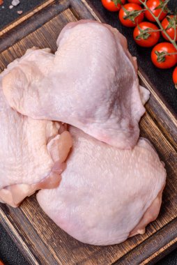 Taze çiğ tavuk butları, koyu beton arka planda tuz ve baharatlar.