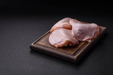 Taze çiğ tavuk butları, koyu beton arka planda tuz ve baharatlar.