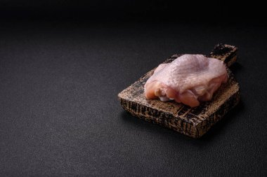 Taze çiğ tavuk butları, koyu beton arka planda tuz ve baharatlar.