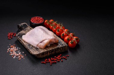 Taze çiğ tavuk butları, koyu beton arka planda tuz ve baharatlar.