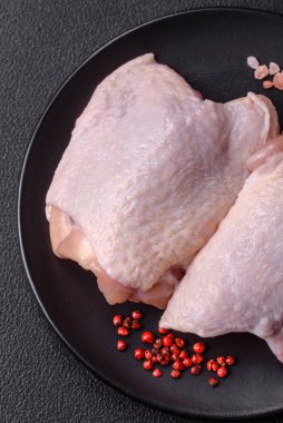 Taze çiğ tavuk butları, koyu beton arka planda tuz ve baharatlar.