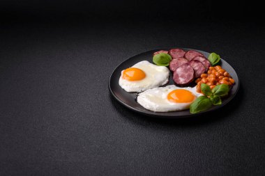 Yağda yumurta, pastırma, fasulye, domates, baharat ve bitkilerle İngiliz kahvaltısı. Güne doyurucu ve doyurucu bir başlangıç.