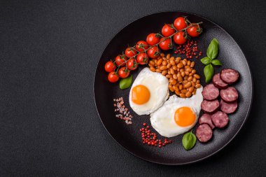 Yağda yumurta, pastırma, fasulye, domates, baharat ve bitkilerle İngiliz kahvaltısı. Güne doyurucu ve doyurucu bir başlangıç.