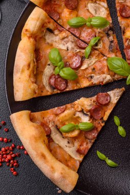 Sosisli, peynirli, domatesli, tuzlu, baharatlı ve çimento kaplı lezzetli bir pizza.