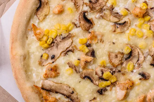 Delicious pizza with corn, cheese, tomatoes and mushrooms, salt, spices and herbs on a dark concrete background