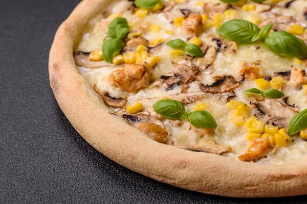 Delicious pizza with corn, cheese, tomatoes and mushrooms, salt, spices and herbs on a dark concrete background