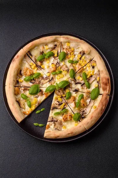 Delicious pizza with corn, cheese, tomatoes and mushrooms, salt, spices and herbs on a dark concrete background