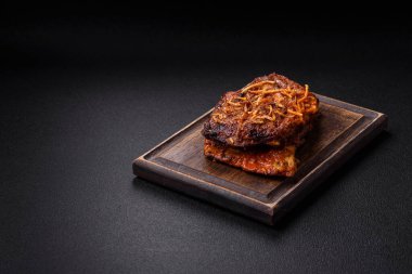 Izgarada pişirilmiş lezzetli domuz ya da biftek pirzolası. Koyu beton arka planda tuz, baharat ve otlarla birlikte.