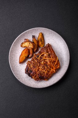 Izgarada pişirilmiş lezzetli domuz ya da biftek pirzolası. Koyu beton arka planda tuz, baharat ve otlarla birlikte.