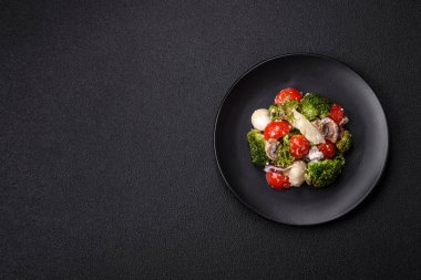 Lezzetli taze salata, bıldırcın yumurtaları, kiraz domatesleri, tuzlu marul yaprakları, baharatlar ve koyu beton arka planda otlar.