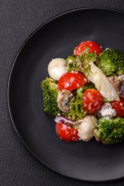 Lezzetli taze salata, bıldırcın yumurtaları, kiraz domatesleri, tuzlu marul yaprakları, baharatlar ve koyu beton arka planda otlar.