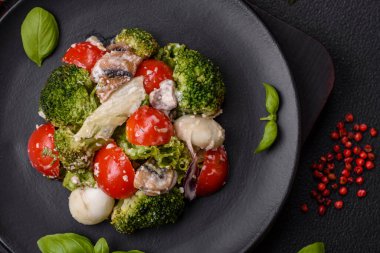 Lezzetli taze salata, bıldırcın yumurtaları, kiraz domatesleri, tuzlu marul yaprakları, baharatlar ve koyu beton arka planda otlar.