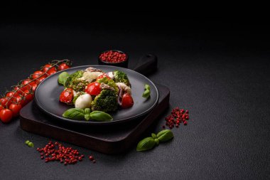 Lezzetli taze salata, bıldırcın yumurtaları, kiraz domatesleri, tuzlu marul yaprakları, baharatlar ve koyu beton arka planda otlar.