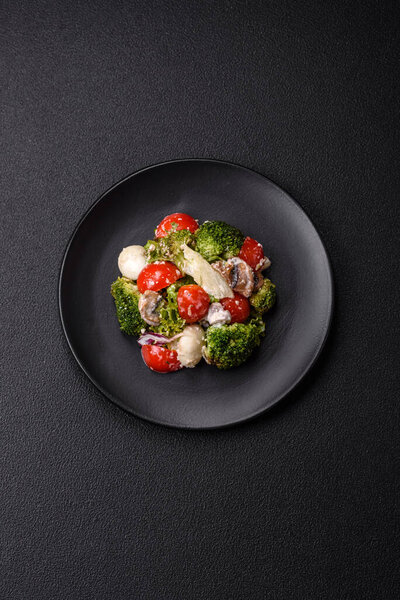 Delicious fresh juicy salad with quail eggs, cherry tomatoes, lettuce leaves with salt, spices and herbs on a dark concrete background