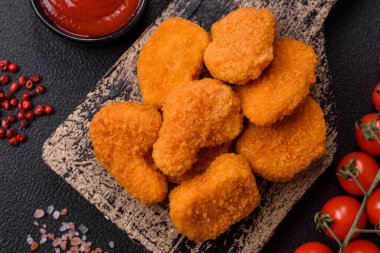 Delicious fresh crispy chicken nuggets on a dark concrete background. Unhealthy food, fast food