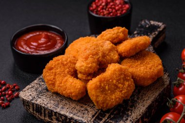 Delicious fresh crispy chicken nuggets on a dark concrete background. Unhealthy food, fast food