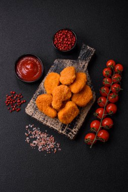 Delicious fresh crispy chicken nuggets on a dark concrete background. Unhealthy food, fast food