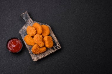 Delicious fresh crispy chicken nuggets on a dark concrete background. Unhealthy food, fast food