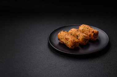 Delicious hearty vegetarian or vegan dish in the form of cutlets or patties consisting of potatoes, carrots, onions and beans on a dark concrete background
