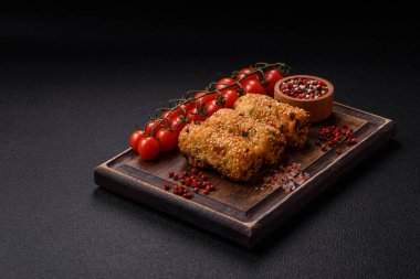 Delicious hearty vegetarian or vegan dish in the form of cutlets or patties consisting of potatoes, carrots, onions and beans on a dark concrete background