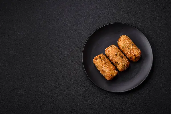 Delicious hearty vegetarian or vegan dish in the form of cutlets or patties consisting of potatoes, carrots, onions and beans on a dark concrete background