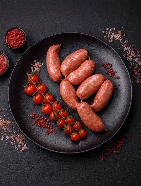 Koyu beton arka planda fırında tavuk ya da domuz sosisi, tuz, baharat ve otlar.