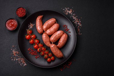Koyu beton arka planda fırında tavuk ya da domuz sosisi, tuz, baharat ve otlar.