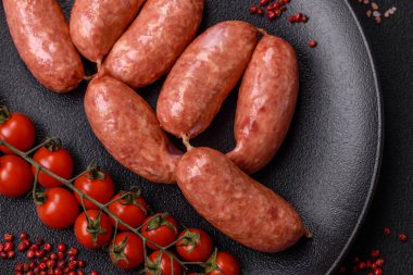 Koyu beton arka planda fırında tavuk ya da domuz sosisi, tuz, baharat ve otlar.