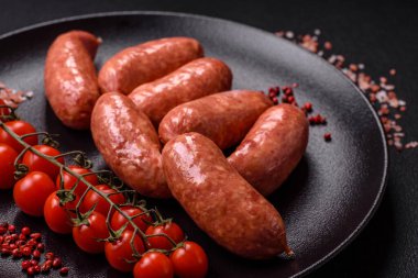 Koyu beton arka planda fırında tavuk ya da domuz sosisi, tuz, baharat ve otlar.