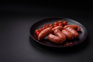 Koyu beton arka planda fırında tavuk ya da domuz sosisi, tuz, baharat ve otlar.