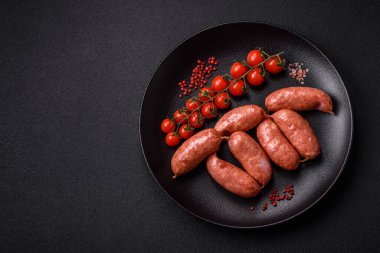 Koyu beton arka planda fırında tavuk ya da domuz sosisi, tuz, baharat ve otlar.