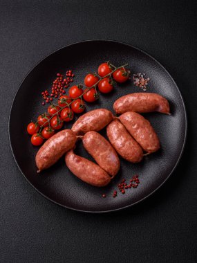 Koyu beton arka planda fırında tavuk ya da domuz sosisi, tuz, baharat ve otlar.