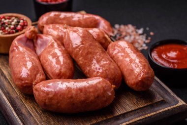 Koyu beton arka planda fırında tavuk ya da domuz sosisi, tuz, baharat ve otlar.