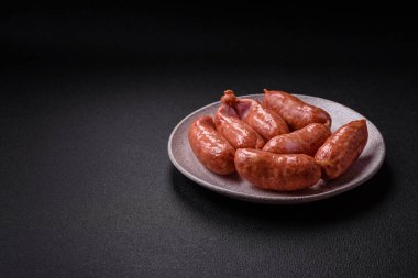 Koyu beton arka planda fırında tavuk ya da domuz sosisi, tuz, baharat ve otlar.