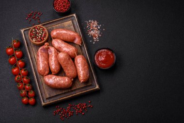 Koyu beton arka planda fırında tavuk ya da domuz sosisi, tuz, baharat ve otlar.